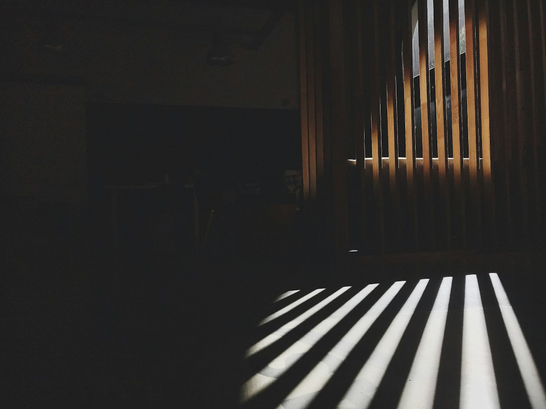 Slats of warm light across a dim surface